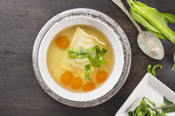 Clear soup with ravioli , carrots and bear garlic