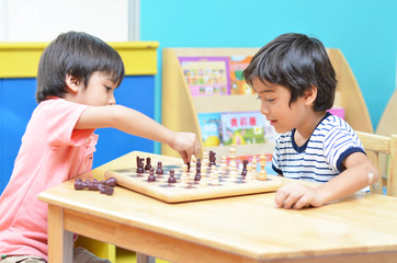 Little siblibg boy playing chess