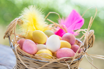 Easter eggs in basket on garden rustic table.Marzipan sweets.
