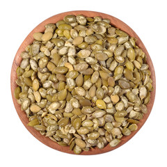 Cleared pumpkin seeds in a wooden bowl on a white