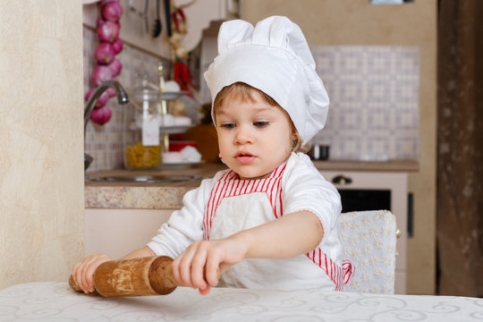 Little girl in apron in the kitchen.