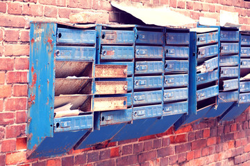 broken mailboxes on an old brick wall