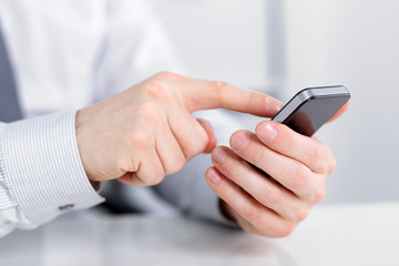 Male hand holding a cell phone and writing sms