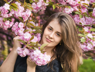 Naklejka premium happy girl in the flowers of sakura