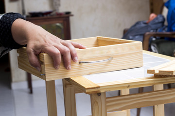A carpenter builds a small white table with a screwdriver