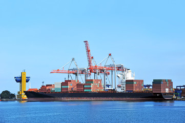 Fototapeta premium Container stack and ship under crane bridge