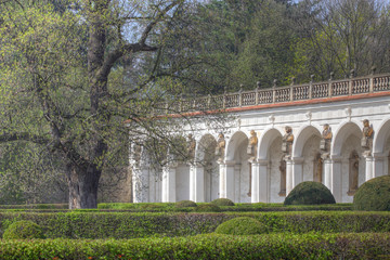 Fototapeta na wymiar Baroque colonnade with statues and green hedges