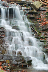 Fototapeta na wymiar Water flowing over rocks in waterfall cascade in a forest