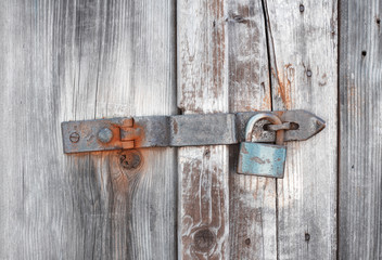 Old wooden door secured by rusty padlock