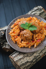 Braised cabbage and meatballs in a glass plate on wooden logs