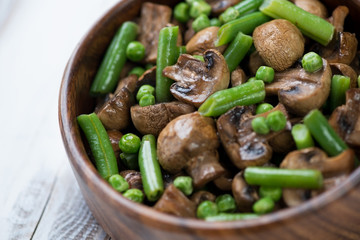 Close-up of fried champignons with peas and beans, studio shot