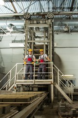 Two men in a safety hats on a factory