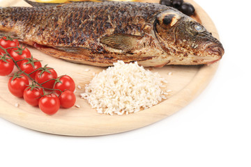 Grilled carp on platter with rice and tomatoes.