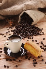 A hot cup of espresso with coffee beans and Cake