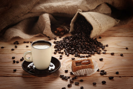 A hot cup of espresso with coffee beans and Cake