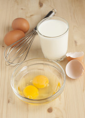 Raw chicken eggs and a glass of milk for cooking omelets.