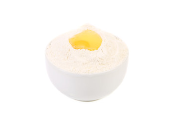 Yellow raw egg yolk on flour in bowl.