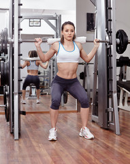 Fototapeta na wymiar Athletic woman doing squats at the gym