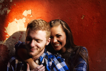 Couple in love hugging and laughing on a red wall