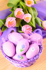 Fototapeta na wymiar Easter decorative eggs in the basket and bouquet of pink tulips
