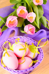 Easter eggs in the basket and bouquet of tulips