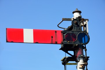 Red rail signal with blue sky
