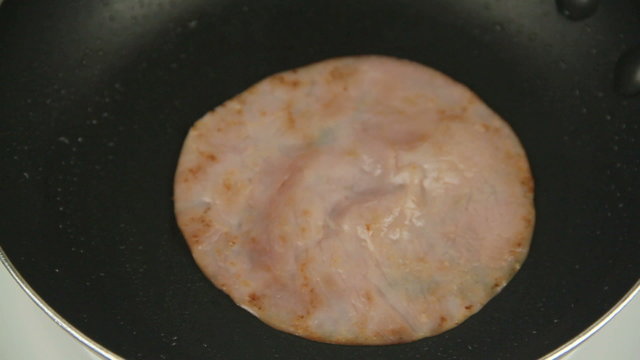 Serving slices of fried ham from the fry pan