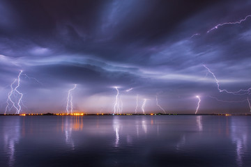 Onweer en bliksem in de nacht over een meer met reflectie