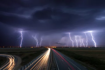 Deurstickers Onweer Onweer en bliksem in de nacht over een snelweg met auto lig
