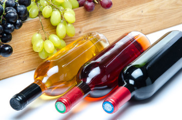 Bottles of wine in front of a wooden box with grapes
