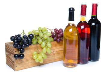 Bottles of wine in front of a wooden box with grapes