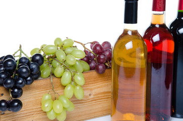 Obraz premium Bottles of wine in front of a wooden box with grapes