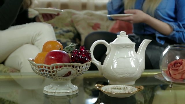 Elegant tea set on the table female friends on the background