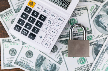 lock and calculator on dollar bill background.