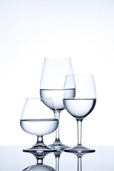 Glassware and bottle filled with water on white background