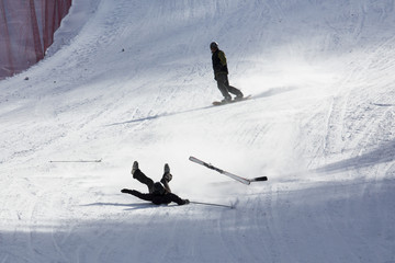 skier falling down white on mountain slope