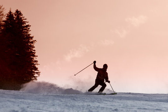 Skier silhouette on a slope at sunset