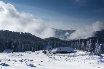 Caban in winter mountain with blue sky and white clouds