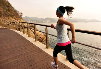 fitness woman running on wooden bridge seaside 