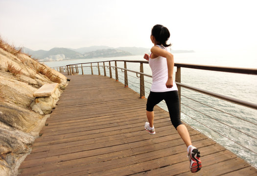 fitness woman running on wooden bridge seaside 