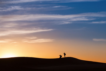 Fototapeta na wymiar Sylwetka fotografów w Saharze na zachód słońca, Maroko