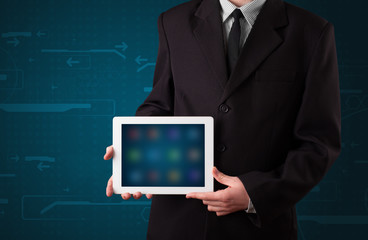 Businessman holding a white modern tablet with blurry apps