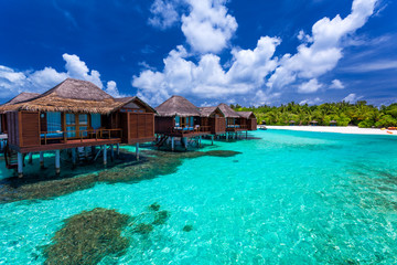 Over water bungalows with steps into green coral lagoon