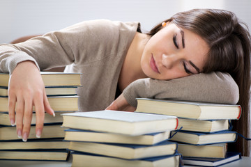 Tired student fell a sleep between many books