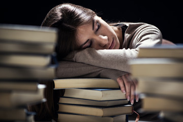 Tired student fell a sleep between many books
