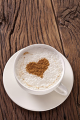 Cup of cappuccino with ground cinnamon in the form of heart.