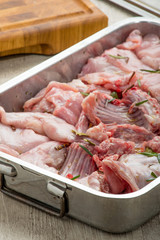 Pezzi di coniglio crudo nella teglia per essere cucinato