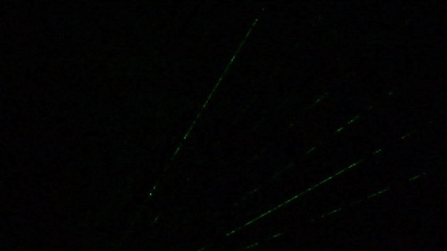 Green laser light flashing on a dark background.