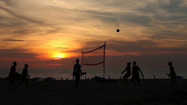 Люди играют в волейбол на пляже вечером