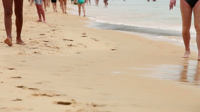 Ноги людей гуляющих по песчаному пляжу